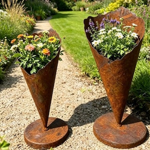 May include: Two cone-shaped planters made of rusted metal, each featuring a circular base. The planters have uneven, jagged top edges and are filled with various colourful flowers, including orange, yellow, white, and purple blossoms.