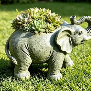 May include: A gray elephant-shaped planter with a textured, mottled finish. The elephant has large ears, a raised trunk, and tusks. A cluster of green succulent plants is planted in the hollow back of the elephant figure.