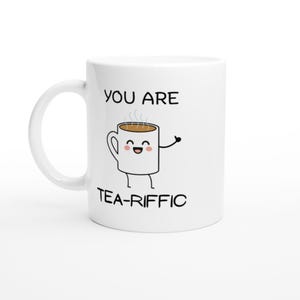 May include: White ceramic mug with a cartoon illustration of a coffee cup with a smiling face, arms, and legs. The mug has the text "YOU ARE TEA-RIFFIC" in black letters.