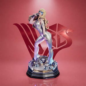 May include: A figurine of a blonde singer wearing a metallic silver jumpsuit and roller skates, holding a microphone. The figure stands on a circular base featuring a small disco ball, set against a red background with a large stylized logo.