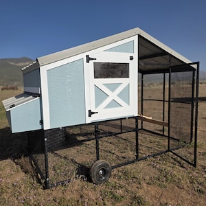May include: A blue and white chicken coop with a metal roof and a black wire mesh enclosure. The coop has a small nesting box and a door with an X-shaped design. It sits on a black metal frame with wheels.