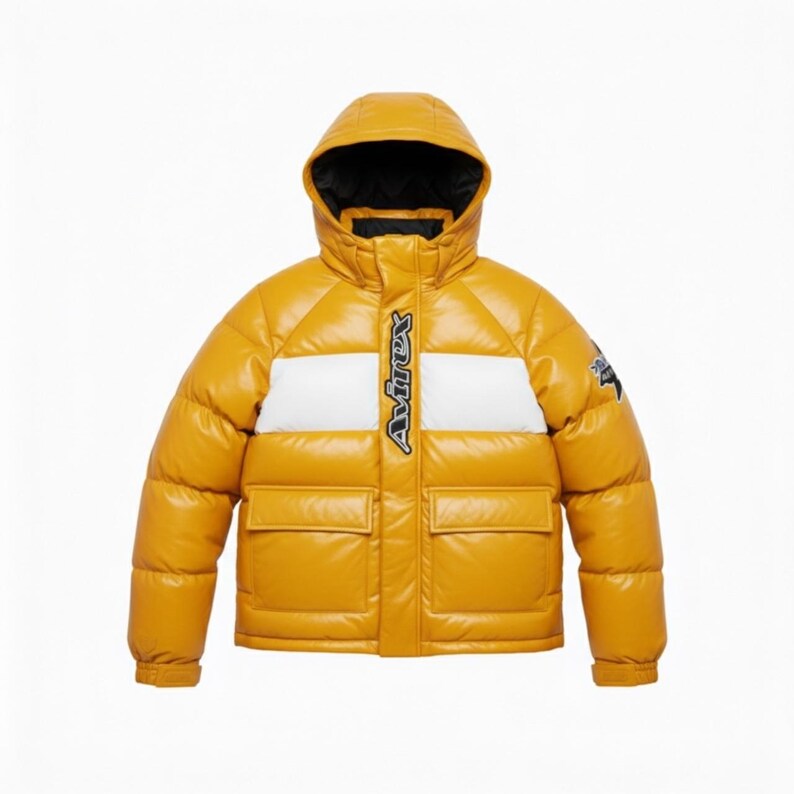 May include: Mustard yellow puffer jacket with a hood and two front pockets. The jacket features a white stripe across the chest with the brand name "Avirex" in black. The jacket has a black interior lining and a small logo on the sleeve.