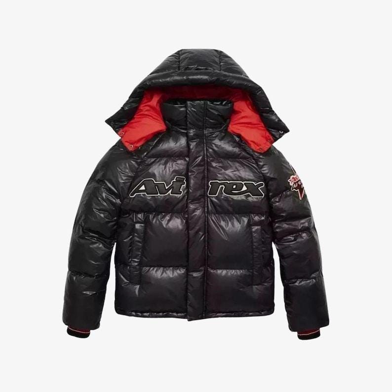 May include: Black puffer jacket with a hood and red lining. The jacket features the text "Avi rex" in white and black lettering across the chest. A small patch is visible on the right sleeve. The jacket has a glossy finish.