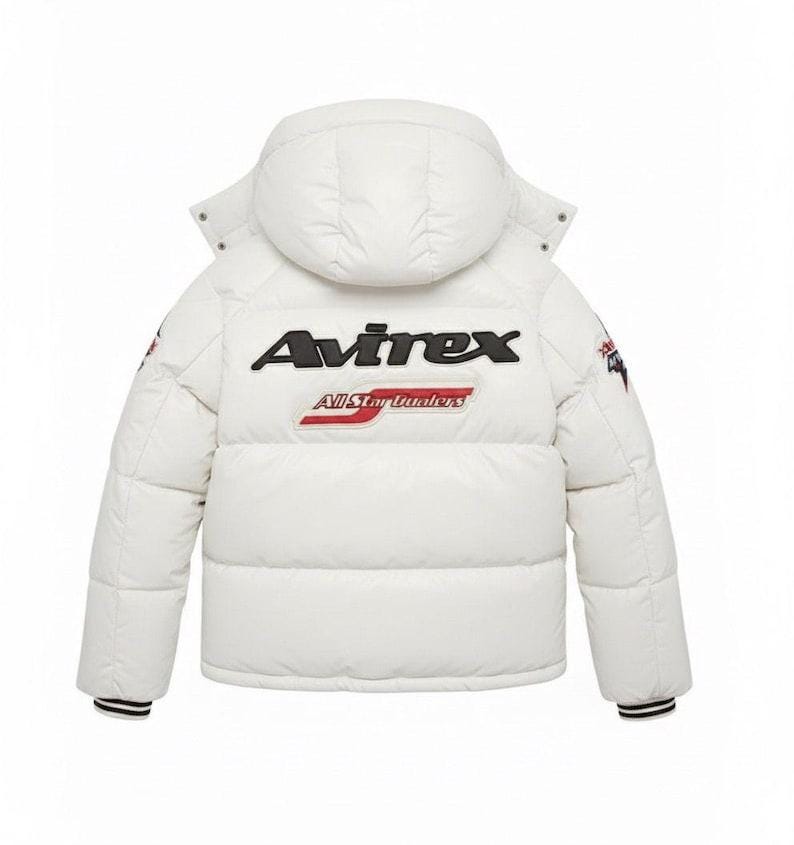 May include: White puffer jacket with a hood, featuring the "Avirex" logo in black and red on the back. The jacket has a quilted design, black and red striped cuffs, and patches on the sleeves. A winter outerwear item.