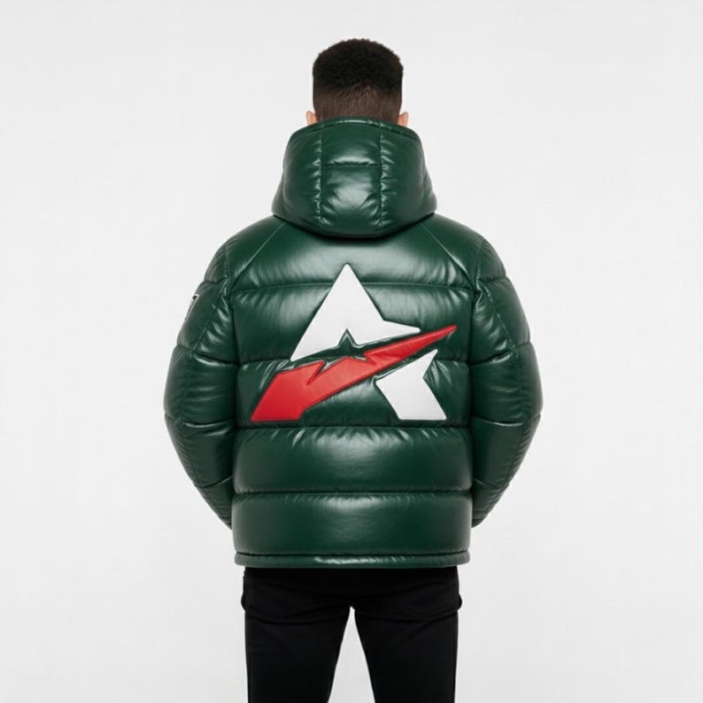 May include: A dark green puffer jacket with a large white and red logo on the back. The jacket has a hood and a shiny, quilted appearance. The person is wearing black trousers.