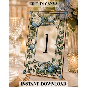 May include: A rectangular table number sign featuring a stained glass style border with blue and white hydrangea flowers and green leaves. The center is clear with the black number 1 printed in the middle. The text EDIT IN CANVA and INSTANT DOWNLOAD appear at the top and bottom.