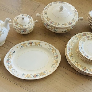Könnte beinhalten: Ein komplettes Vintage-Porzellan-Geschirrset mit floralen und goldenen Verzierungen. Das Set enthält eine Teekanne, eine Zuckerdose, eine Servierschüssel, Teller, Schalen, Salz- und Pfefferstreuer und eine ovale Platte.