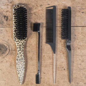 Könnte beinhalten: Eine Sammlung von Haarstyling-Werkzeugen, darunter eine Bürste mit Leopardenmuster-Griff und schwarzen Borsten, eine kleine schwarze Bürste und zwei schwarze Kämme. Die Werkzeuge sind auf einer Holzoberfläche angeordnet.
