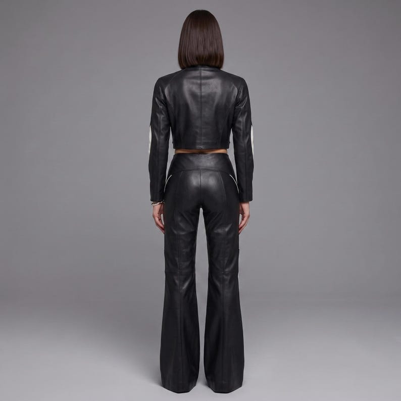 May include: A black leather outfit consisting of a cropped long-sleeve jacket and high-waisted flared trousers. The jacket features white piping along the sleeves, while the trousers include white piping details along the hips and legs.