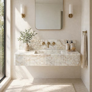 May include: A modern bathroom interior featuring a marble vanity with a built-in sink and gold fixtures. A rectangular mirror hangs above the sink, flanked by sconces. A fluffy rug sits on the floor, and a towel rack is on the right.