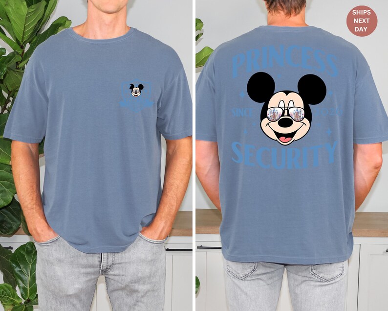 May include: A blue short-sleeved t-shirt featuring a Mickey Mouse graphic on the front and back. The front has a small Mickey Mouse design, while the back displays a larger Mickey Mouse wearing sunglasses with the text "PRINCESS SECURITY".