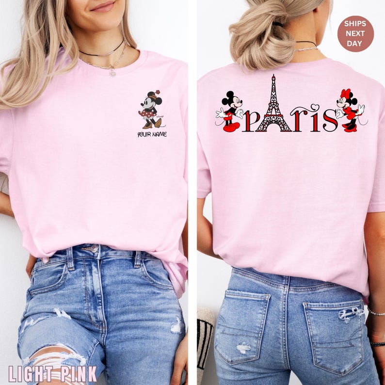 May include: Light pink t-shirt featuring a Minnie Mouse graphic with the text "YOUR NAME" on the front. The back of the shirt displays Mickey and Minnie Mouse with the Eiffel Tower and the word "Paris".