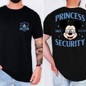 May include: Black t-shirt featuring a Mickey Mouse graphic with sunglasses and the text "PRINCESS SECURITY SINCE 2026" on the back. The front has a shield design with Mickey Mouse and the words "PRINCESS SECURITY".