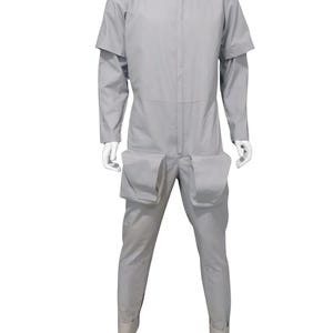 K&ouml;nnte beinhalten: Hellgrauer Overall mit hohem Kragen und langen &Auml;rmeln. Der Overall hat gro&szlig;e Taschen an den Oberschenkeln und einen Rei&szlig;verschluss vorne. Die &Auml;rmel haben ein einzigartiges Design mit angebrachten Schulterumh&auml;ngen. Die Manschetten sind an den Kn&ouml;cheln hochgekrempelt.