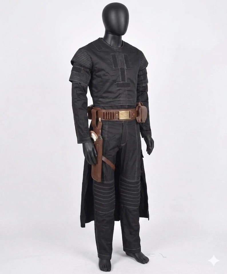 K&ouml;nnte beinhalten: Ein schwarzes Kost&uuml;m, das auf einer Schaufensterpuppe ausgestellt ist. Das Outfit umfasst ein lang&auml;rmliges Oberteil, eine Hose und einen G&uuml;rtel mit Taschen. Eine Halterung mit einer Waffe ist am Bein befestigt. Das Kost&uuml;m hat ein futuristisches Design mit sichtbaren N&auml;hten und gepolsterten Details.