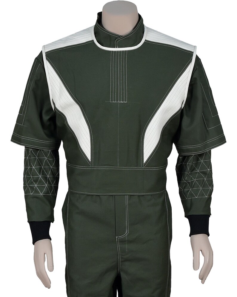 May include: A dark olive green jumpsuit featuring a high collar and white quilted panels on the shoulders and chest. The sleeves have a geometric triangular stitched pattern on the forearms, finished with black ribbed cuffs and white contrast stitching.