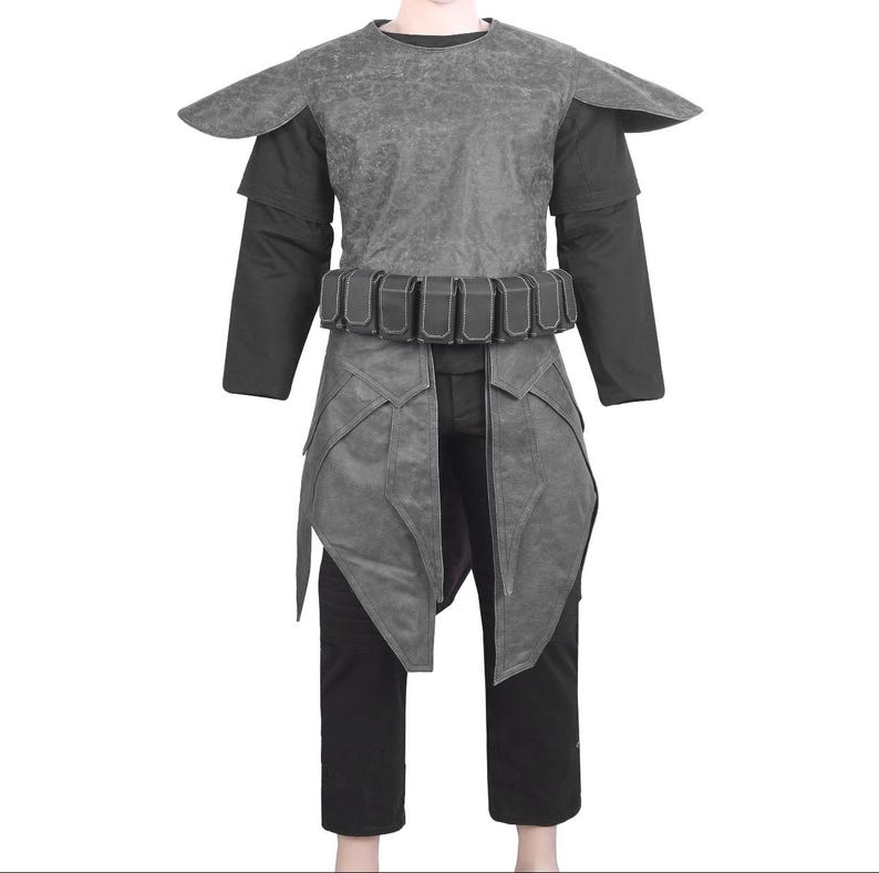 Pu&ograve; includere: Un costume cosplay grigio con un design a strati. L'outfit include un pezzo di spalla strutturato, una camicia nera a maniche lunghe, una cintura con pi&ugrave; tasche e un indumento inferiore a forma di gonna. I pantaloni neri completano l'ensemble.