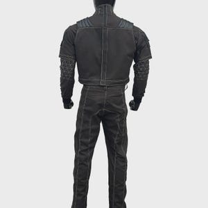 May include: A black tactical-style jacket and matching trousers set featuring prominent white contrast stitching. The jacket includes shoulder padding, a high collar, and geometric white line patterns on the sleeves. The trousers have a straight-leg fit.