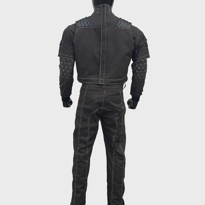 May include: A black tactical-style jacket and matching trousers set featuring prominent white contrast stitching. The jacket includes shoulder padding, a high collar, and geometric white line patterns on the sleeves. The trousers have a straight-leg fit.