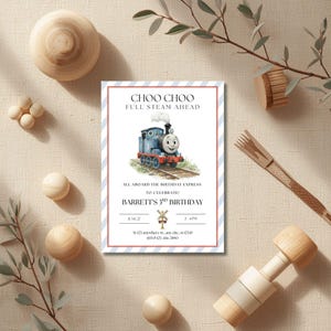 May include: A birthday invitation with a blue and red striped border. The invitation features a cartoon illustration of a blue train with the text "CHOO CHOO FULL STEAM AHEAD". The invitation is for Barrett's 3rd birthday.