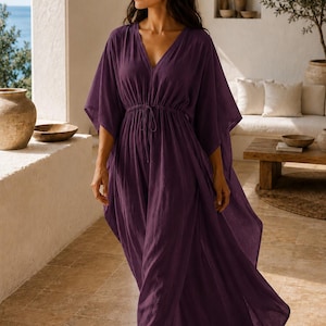 Puede incluir: Un vestido caft&aacute;n largo de color morado intenso con escote en V, mangas anchas estilo kimono y cintura con cord&oacute;n ajustable y lazos finos. La prenda est&aacute; confeccionada con un tejido ligero y texturizado que cae holgadamente hasta los tobillos.