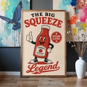 May include: A framed poster featuring a cartoon ketchup bottle character with a face, arms, and legs, giving a thumbs up. The text reads THE BIG SQUEEZE, TOMATO KETCHUP 100% DELICIOUS, KITCHEN CLASSIC, and Legend in red and black on a cream background.