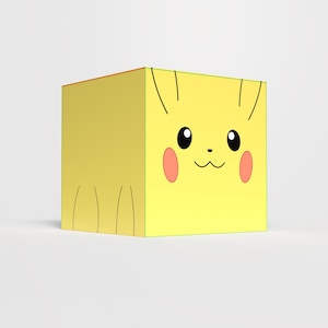 Puede incluir: Un objeto amarillo en forma de cubo con un diseño de cara de Pikachu. El diseño incluye ojos negros, mejillas rosas, una pequeña nariz negra y una boca sonriente. Líneas negras representan las orejas y la cola de Pikachu.