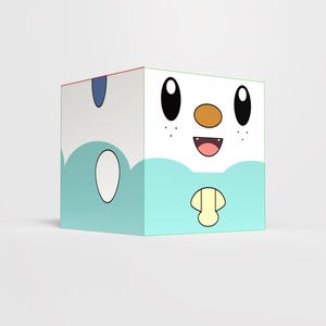 Puede incluir: Un juguete en forma de cubo con un diseño de personaje de dibujos animados. El cubo tiene una cara blanca con ojos negros, una nariz marrón y una boca sonriente. La parte inferior es azul claro con detalles blancos y azules.
