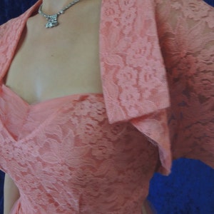Puede incluir: Un vestido vintage de encaje color melocot&oacute;n con un bolero a juego. El vestido presenta un escote coraz&oacute;n y un corpi&ntilde;o ajustado. Un collar plateado brillante a&ntilde;ade un toque de elegancia. Perfecto para una ocasi&oacute;n especial.