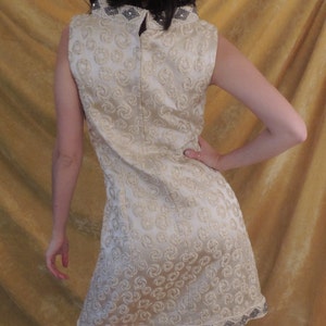 Puede incluir: Un vestido sin mangas con cuello alto y un ribete de cuentas. El vestido est&aacute; hecho de una tela blanca con un sutil patr&oacute;n de espiral.