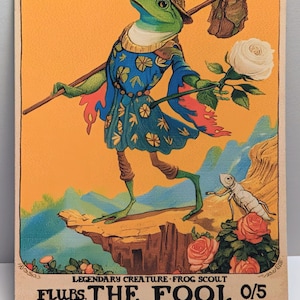 Può includere: Una carta collezionabile rettangolare raffigurante una rana con una tunica blu a motivi e un cappello, che trasporta un bastone con una borsa e una rosa bianca. Il testo della carta recita Flubs, the Fool, Legendary Creature Frog Scout, 0/5.