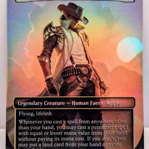 Könnte beinhalten: Holografische Sammelkarte mit "Kellan, the Kid". Die Karte zeigt eine Figur mit Cowboyhut und Duster vor einem Sonnenuntergang. Text enthält "Legendary Creature - Human Faerie Rogue" und Spielanweisungen. Die Karte hat 3/3 Stärke und Widerstand.