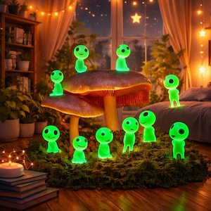 May include: A whimsical indoor scene features glowing green figurines resembling forest spirits, arranged on a mossy base and a large mushroom. The figurines have round heads and smiling faces. Fairy lights and a starry night scene are visible in the background.