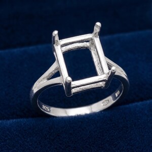 May include: A silver ring setting with a square center and four prongs. The ring is marked with "925" and has a split shank design. The ring is designed to hold a square gemstone.