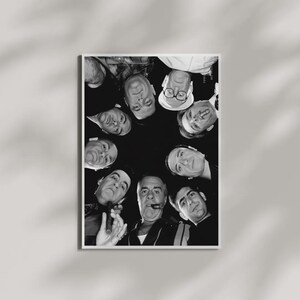 May include: A black and white photographic print featuring a low-angle, circular composition of several individuals looking downward. The subjects are arranged in a ring, with some wearing hats and glasses, and one individual holding a cigar.