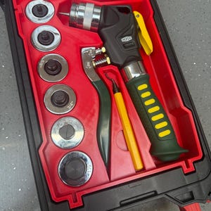 Könnte beinhalten: Ein schwarzer und roter Kunststoffkoffer mit einem Metall-Rohraufweiter mit grün-gelbem Griff, einem gelben Entgrater und sechs kreisförmigen Metall-Aufweitköpfen, die mit den Größen 3/8, 1/2, 5/8, 3/4, 7/8 und 1 1/8 Zoll gekennzeichnet sind.