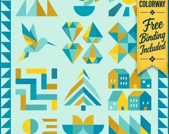 May include: A quilt featuring a light blue background with geometric patterns in yellow, teal, and light blue. Designs include a hummingbird, sun, diamonds, houses, and trees. A yellow banner on the right reads SHOP EXCLUSIVE COLORWAY and FREE Binding Included.