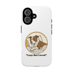 May include: White phone case featuring a graphic of a brown and white dog resting on a pillow, within a gold circle. The text "Lazy But Loved" is below the graphic.