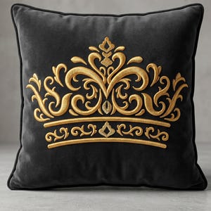 May include: A square, black velvet pillow with a gold embroidered crown design. The crown features ornate swirls and details, creating a regal aesthetic. The pillow has a dark border, adding contrast to the design. Home decor item.
