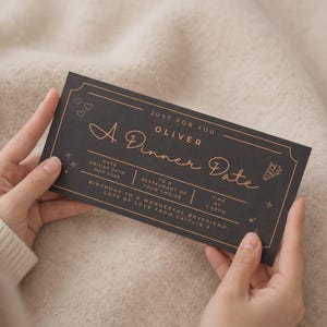 May include: A rectangular black gift voucher with copper-coloured text and line art. The text reads: JUST FOR YOU, OLIVER, A DINNER DATE, DATE FRIDAY 24TH MAY 2026, TO A RESTAURANT OF YOUR CHOICE, TIME 7:00PM, BIRTHDAY TO A WONDERFUL BOYFRIEND.