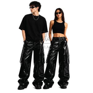 May include: Two people in black outfits. The person on the left is wearing a black t-shirt and shiny black cargo trousers. The person on the right is wearing a black crop top and shiny black cargo trousers. Both are wearing black sunglasses.