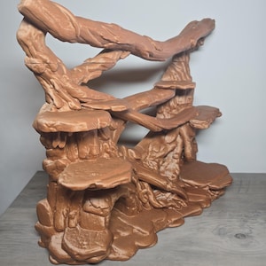 May include: A light brown, three-dimensional printed structure featuring a series of interconnected platforms and branches that mimic a natural tree-like habitat. The object has a textured surface with multiple levels, including flat ledges and a hollow base.