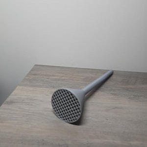 May include: A light gray funnel featuring a wide, circular opening covered with a fine, grid-like mesh pattern and a long, slender, cylindrical stem extending from the base. The object is constructed from a solid, matte-finished material.
