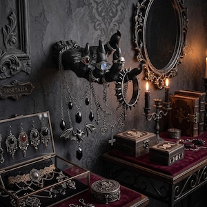 May include: A gothic display with a black hand sculpture wearing rings and a spiked bracelet. Necklaces with pendants hang below. Jewellery boxes and a mirror complete the dark aesthetic.