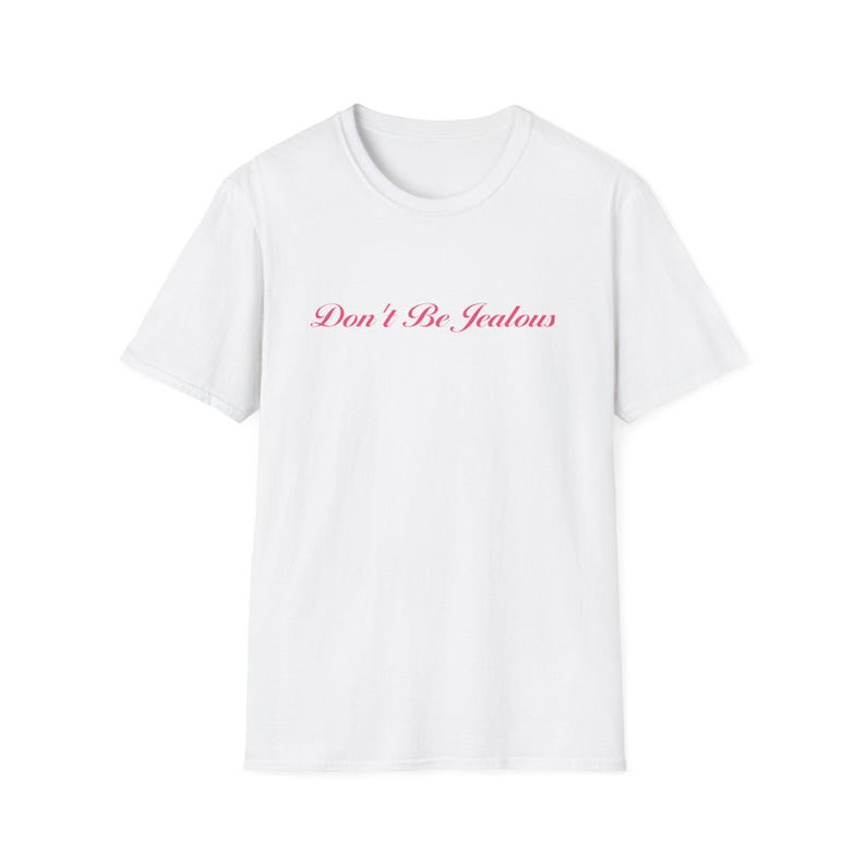 Peut inclure: T-shirt blanc avec l'inscription "Don't Be Jealous" en rose en cursive sur la poitrine. Le t-shirt a un col rond et des manches courtes. Le texte est centr&eacute; sur le devant du v&ecirc;tement.