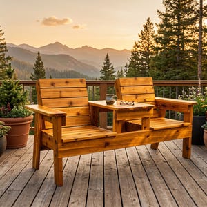 May include: A wooden two-seater bench with a small table in the middle, perfect for outdoor relaxation. The bench is made of light brown wood and is set on a wooden deck. A mug and glasses rest on the table.