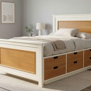 May include: A bed frame featuring a white finish with natural wood-toned panels on the headboard and footboard. The base includes six integrated storage drawers with a matching wood finish, topped with a mattress, pillows, and a neutral blanket.