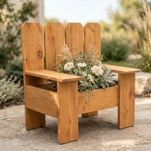 May include: A light brown wooden chair-shaped planter with a high back featuring four vertical slats. The seat area is a rectangular box filled with a variety of white flowers, green foliage, and tall dried grasses, creating a decorative display.