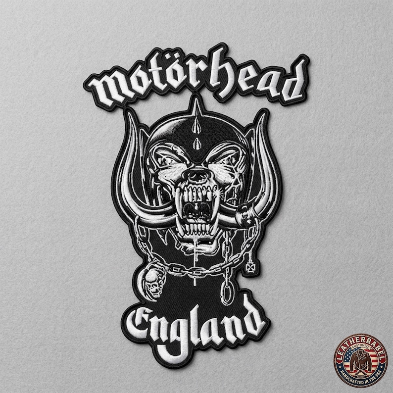 K&ouml;nnte beinhalten: Schwarz-wei&szlig;er, gestickter Aufn&auml;her mit dem Wort "mot&ouml;rhead" &uuml;ber einem Totenkopf-Design. Das Wort "England" steht darunter. Dieser Aufn&auml;her ist zum Aufn&auml;hen auf Kleidung oder Taschen bestimmt.