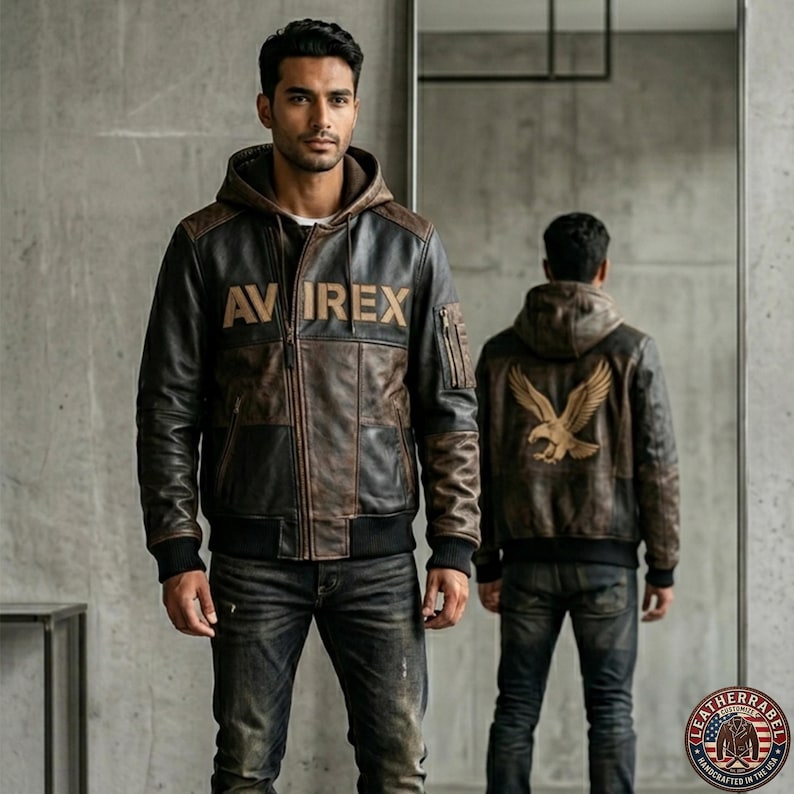 May include: A brown and black leather jacket with a hood. The jacket has the text "AVIREX" on the front and an eagle design on the back. It is a bomber-style jacket with ribbed cuffs and hem.